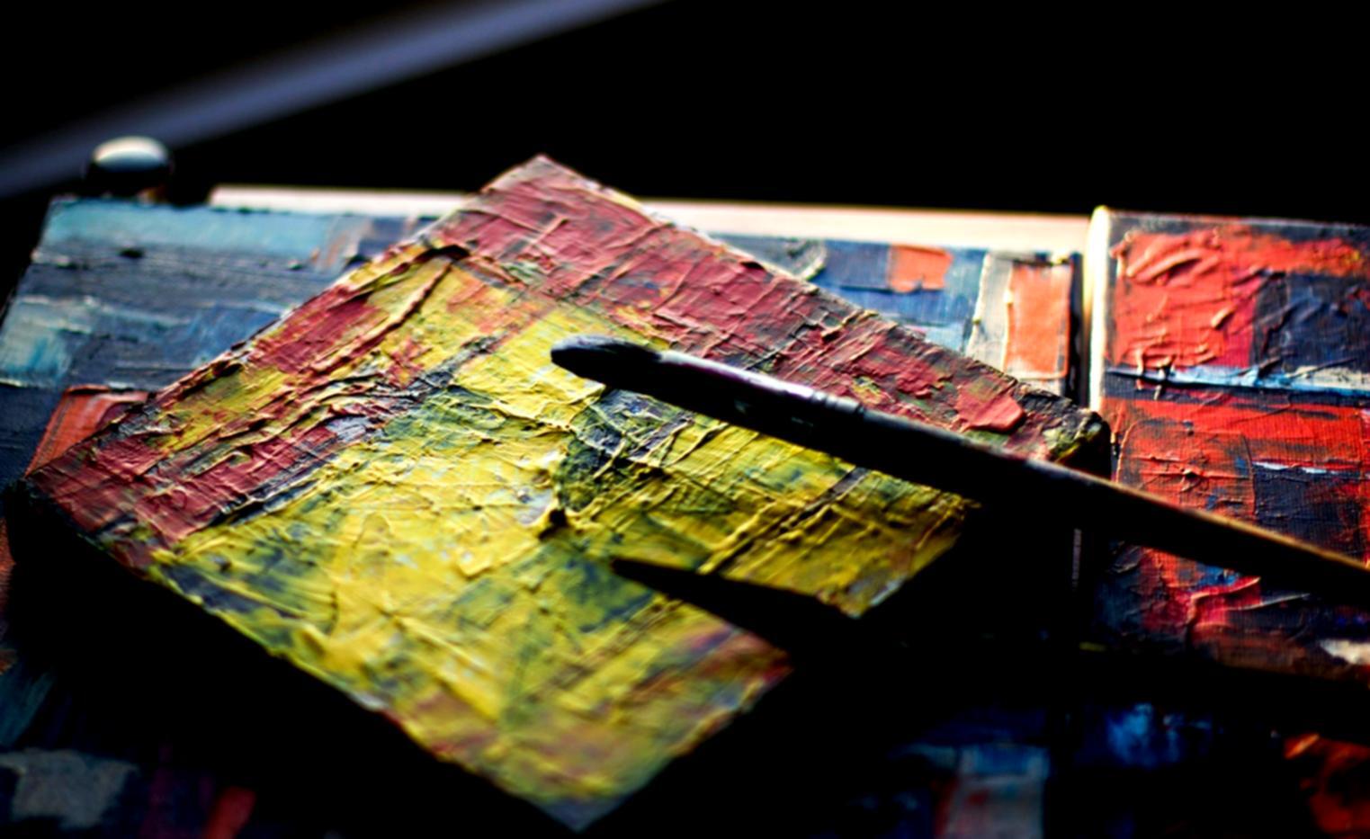 Detailaufnahme von Aquarellfarben und Pinseln auf Papier mit Farbverläufen